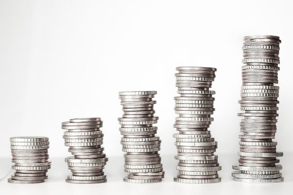 Pilas de monedas de distinta altura sobre fondo blanco