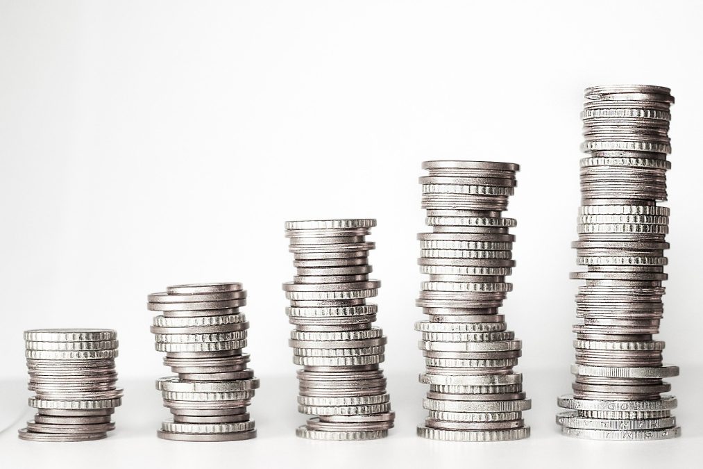 Pilas de monedas de distinta altura sobre fondo blanco